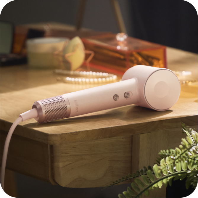 White handheld device with a cable on a wooden surface, blurred background