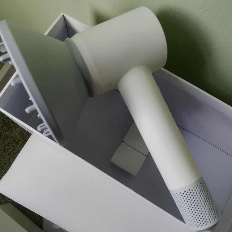 White hair dryer with nozzle attachment on a white surface