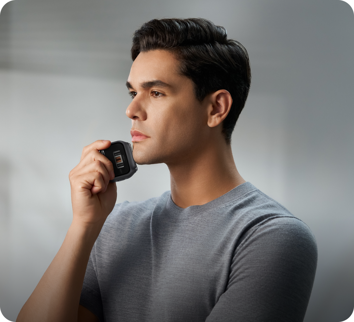 Man holding a black device to his ear against a gray background