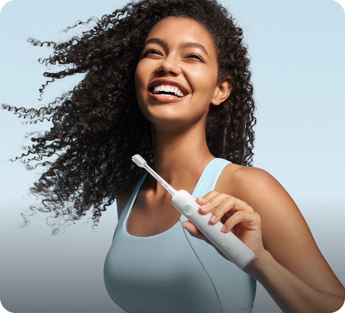 Woman holding a white electric toothbrush against a light blue background