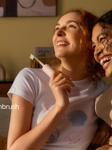 Two people sitting together holding electric toothbrushes with 'Laifen' branding.