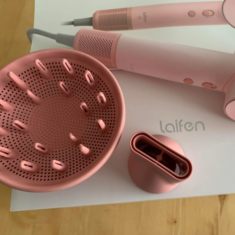 Pink hair dryer and attachments on a white surface with 'laifen' branding.