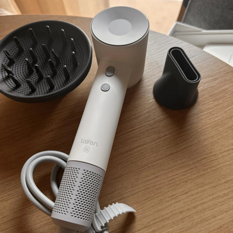 White handheld hair dryer with attachments on a wooden surface