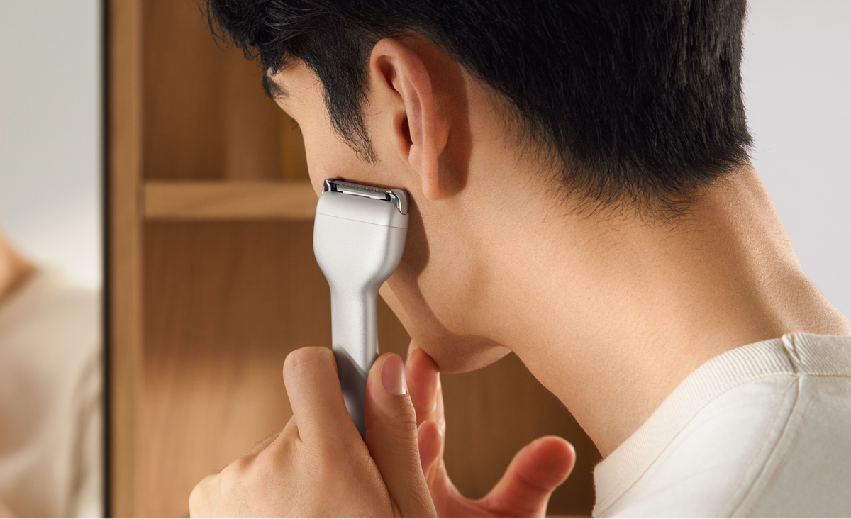 Person using an electric razor in front of a mirror