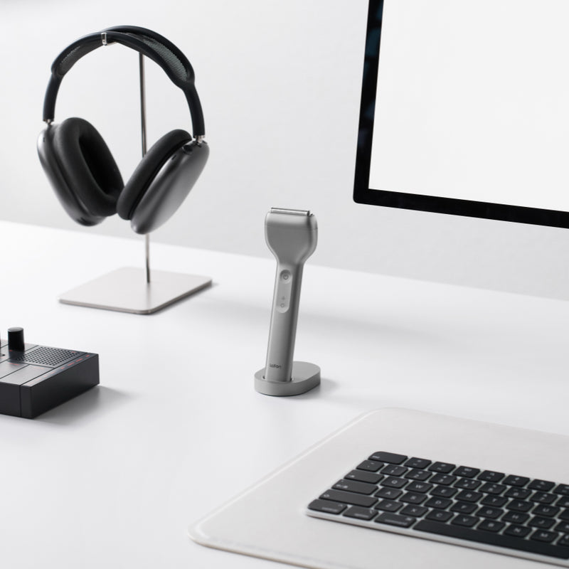 Desk setup with headphones, laptop, and other electronic devices on a white surface.